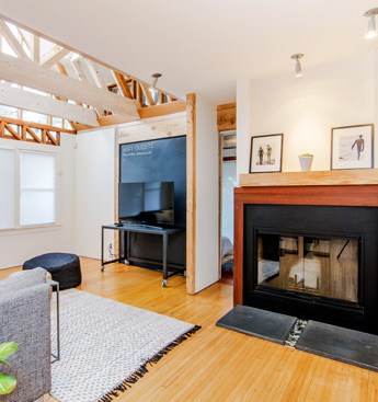 Inside the living room of an Airbnb rental property that has a fireplace and a grey rug.