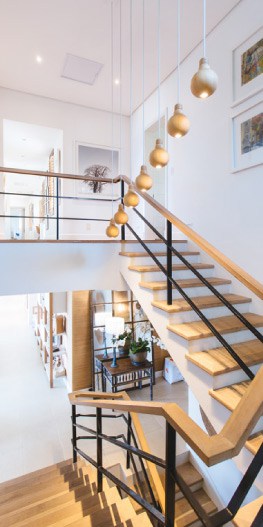 Staircase inside an Airbnb rental property with black railings and an ornamental lighting fixture.