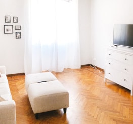 Living room inside an Airbnb rental with all-white furniture and golden-colored wood flooring.
