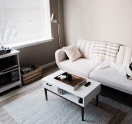 Living room inside an Airbnb vacation rental with all white furniture including a white couch, coffee table, and a white and tan colored rug.