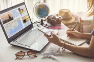 Young woman planning vacation trip and searching information or booking an hotel on a smart phone and laptop