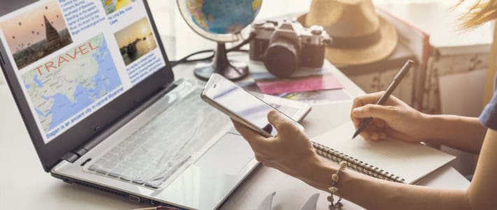 Young woman planning vacation trip and searching information or booking an hotel on a smart phone and laptop