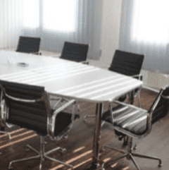 Board room table with rolling chairs after being professionally cleaned by The Magic Helpers.