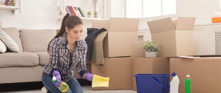 Airbnb Cleaning Services: How Should You Clean a Rental House Before Moving In? Lady cleaning a rental house by mopping the floors with a sponge and a spray bottle full of cleaning products.