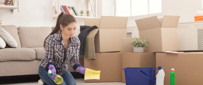 Lady cleaning a rental house by mopping the floors with a sponge and a spray bottle full of cleaning products.