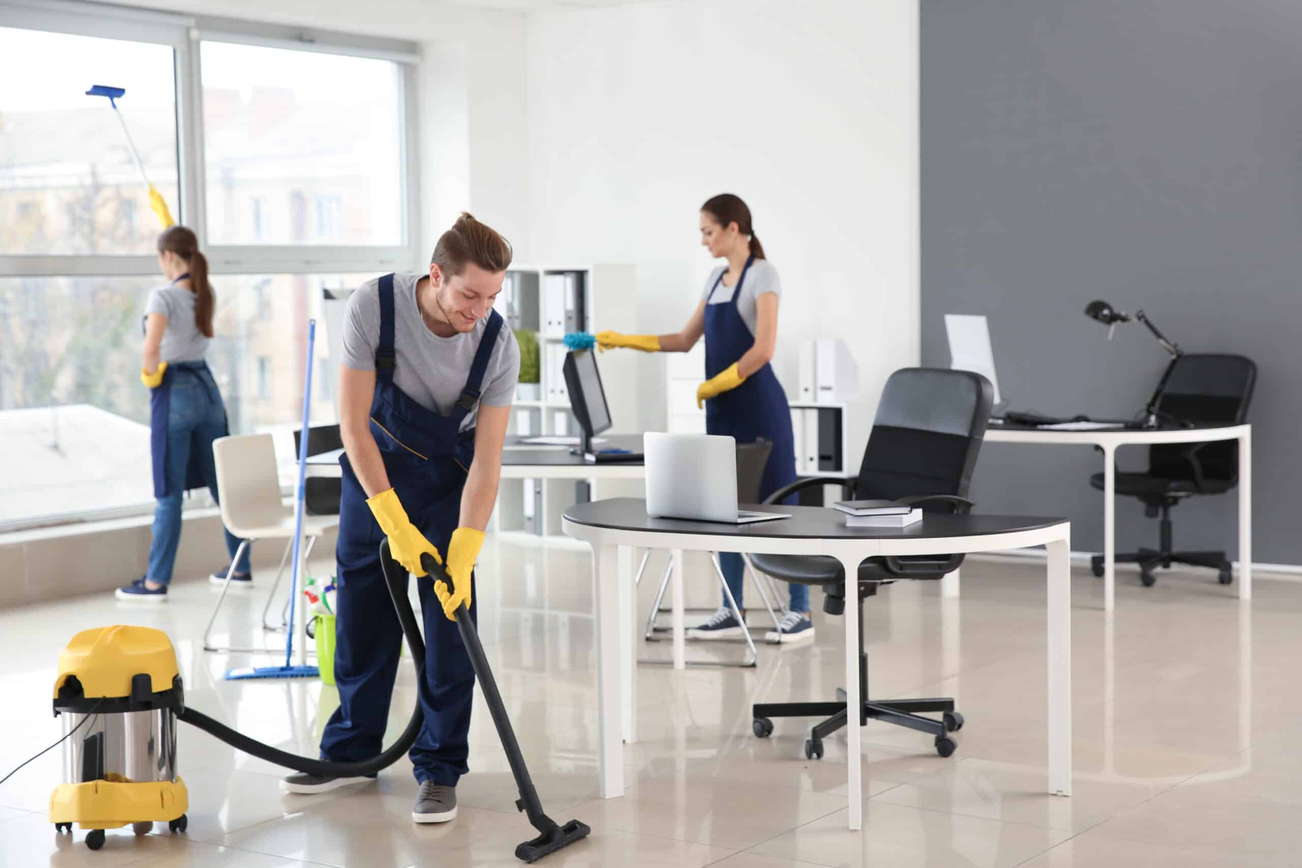 5 Reasons To Outsource Your Office Cleaning Three members of The Magic Helpers team dusting and vacuuming an office space.
