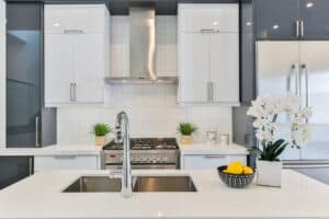 Airbnb kitchen with white countertops, white backsplash, and a white orchid sitting next to a bowl of lemons.