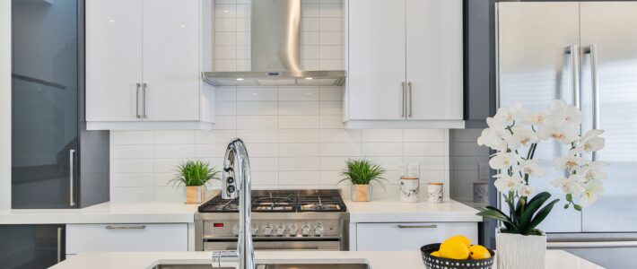 Airbnb kitchen with white countertops, white backsplash, and a white orchid sitting next to a bowl of lemons.