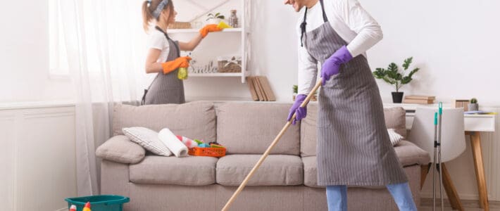 Two members of The Magic Helpers residential cleaning team mopping and dusting a customer's home.