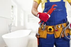 Airbnb plumbing technician wearing a utility belt and holding a wrench.