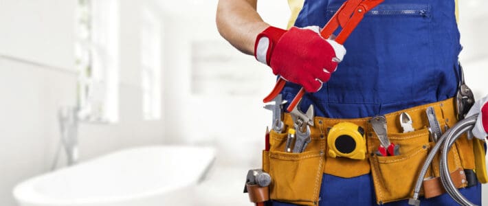 Airbnb plumbing technician wearing a utility belt and holding a wrench.