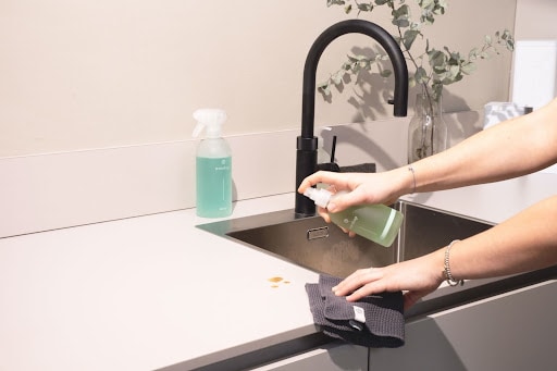 Person wiping down a kitchen counter in an Airbnb rental.
