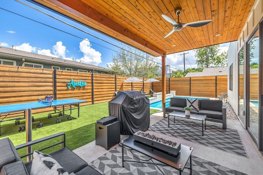 Back patio of an Airbnb property in Austin that has a covered porch, a swimming pool, and a ping pong table.