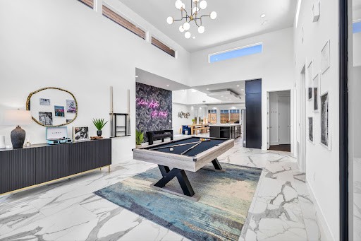 Airbnb living room with marble flooring, a blue and grey rug, a pool table, and a modern chandelier. 
