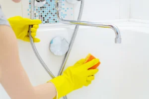 Person using a sponge to clean the interior of a bathtub.